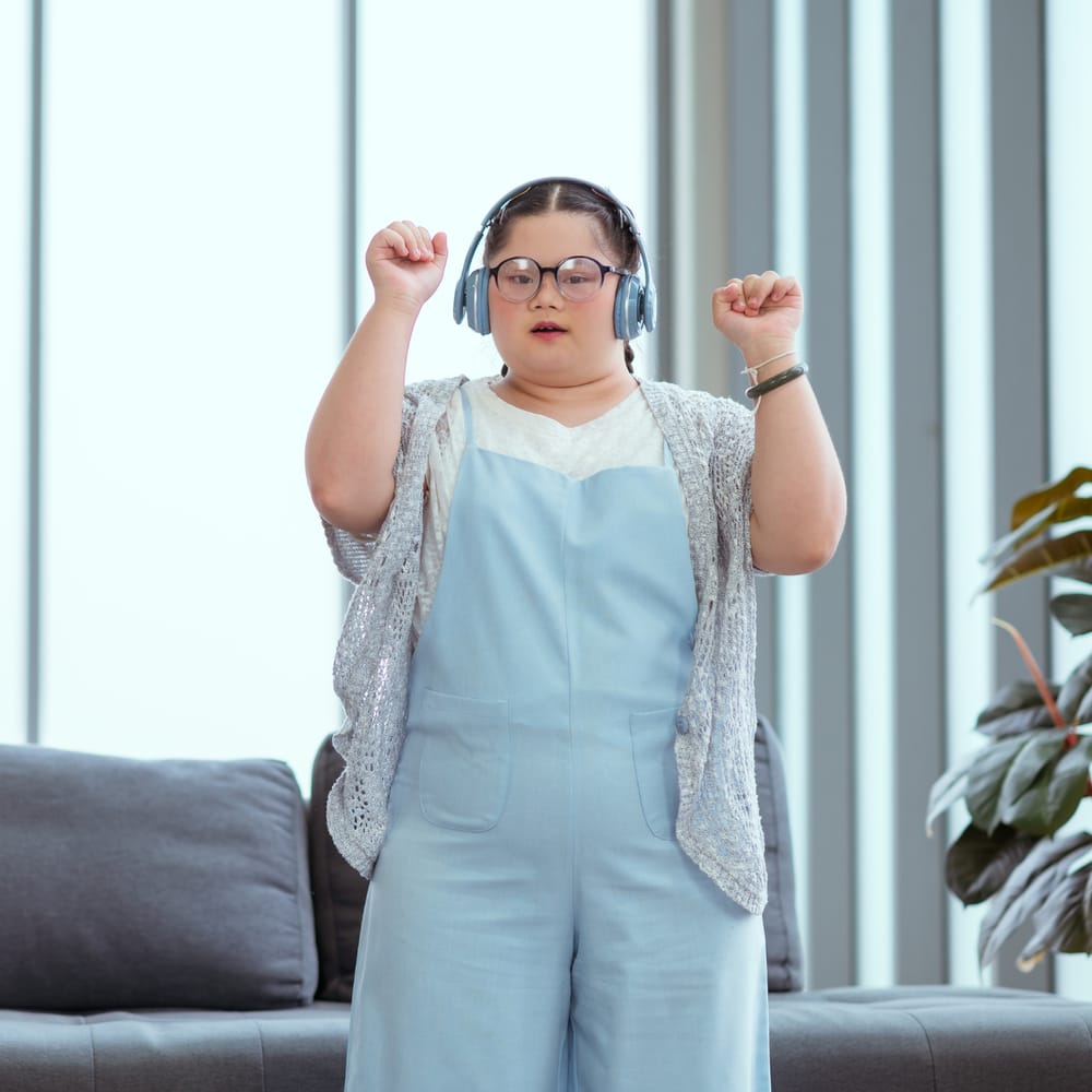 Young woman wearing headphones and dancing joyfully at home