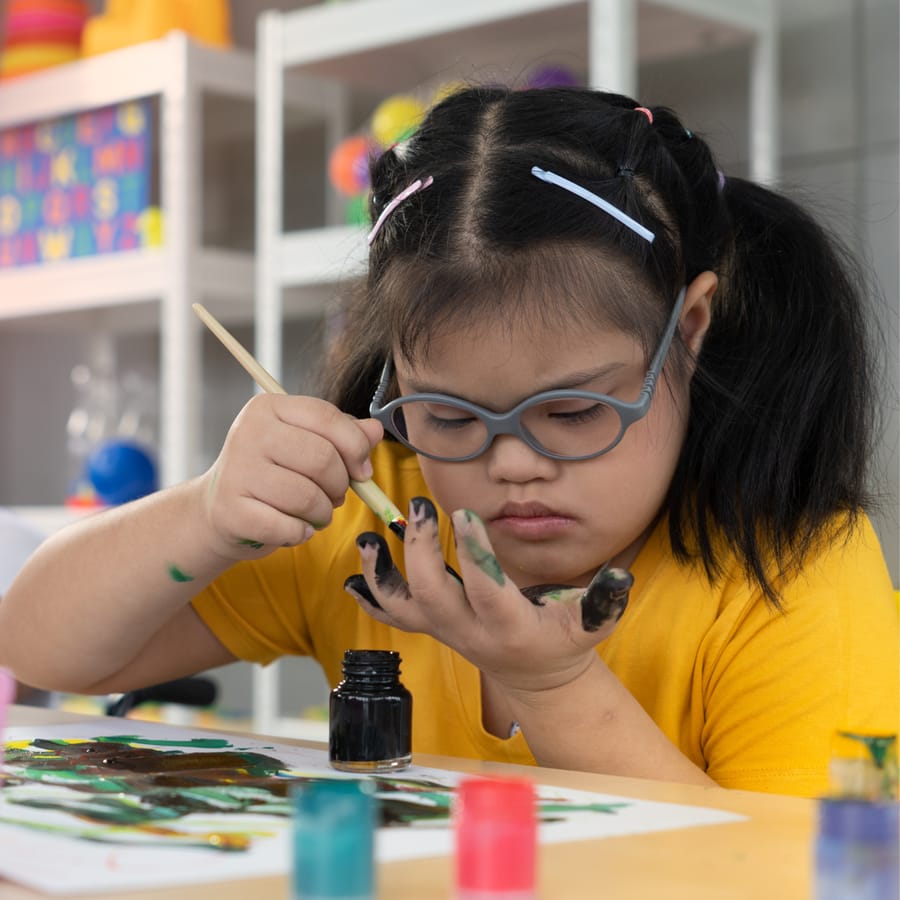 Girl in glasses carefully painting with focused concentration